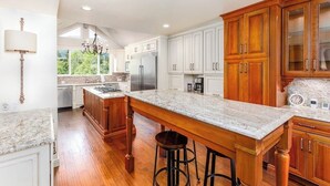 Una cocina con armarios de madera, encimera de mármol y una isla grande con taburetes.