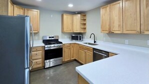 A kitchen with wooden cabinets, a stainless steel refrigerator, a microwave, a stove, and a dishwasher. - Lower Level of the Monarch Estate for Smaller Groups (Girdwood)