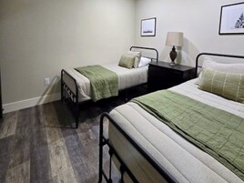 Un dormitorio con dos camas, una mesita de noche con lámpara y un cuadro en la pared.