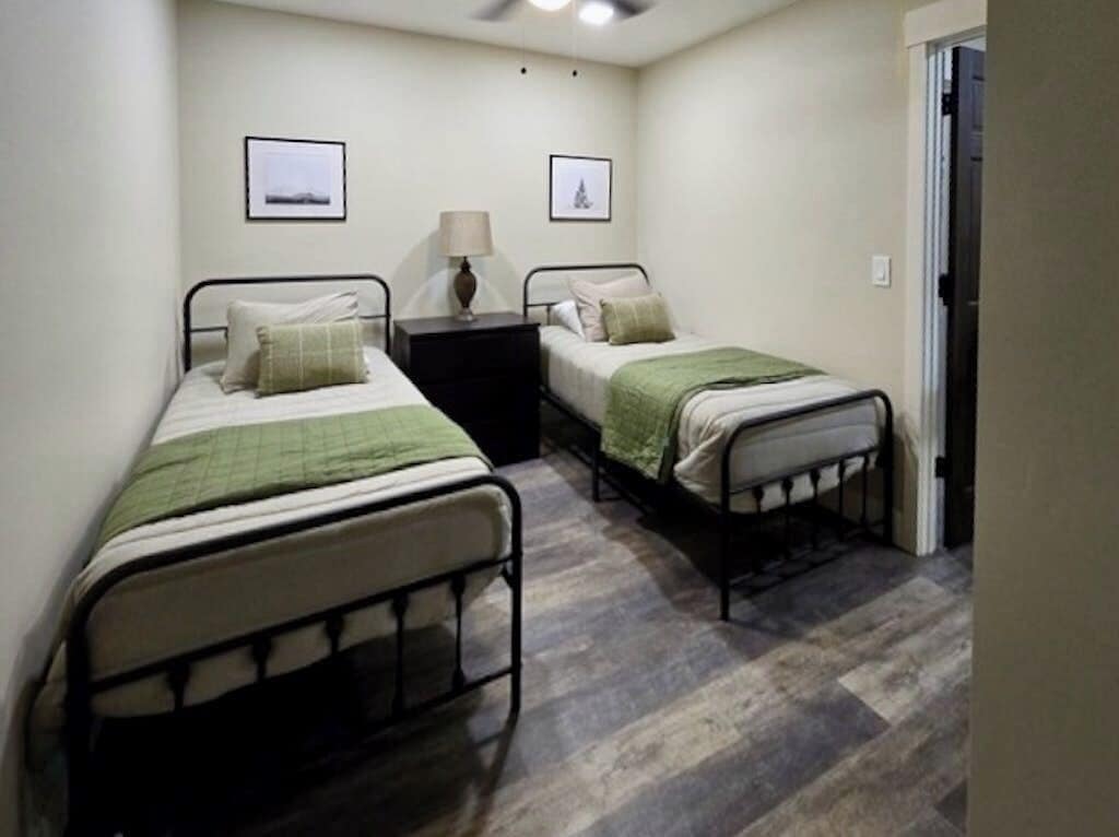 A bedroom with two single beds, a nightstand, and a ceiling fan.