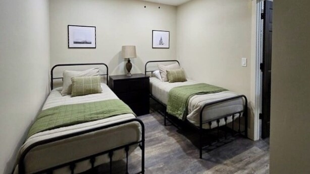 A bedroom with two single beds, a nightstand, and a ceiling fan. - Lower Level of the Monarch Estate for Smaller Groups (Girdwood)