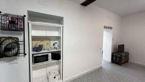 A hallway with a white wardrobe, a microwave, and a small cabinet.