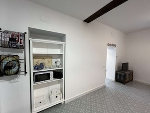 A hallway with a white wardrobe, a microwave, and a small cabinet.