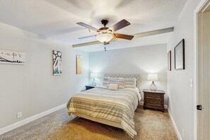 A bedroom with a bed, nightstands, a ceiling fan, and wall art. - Wood-floor Condo w/ Direct Lift Access (Girdwood)