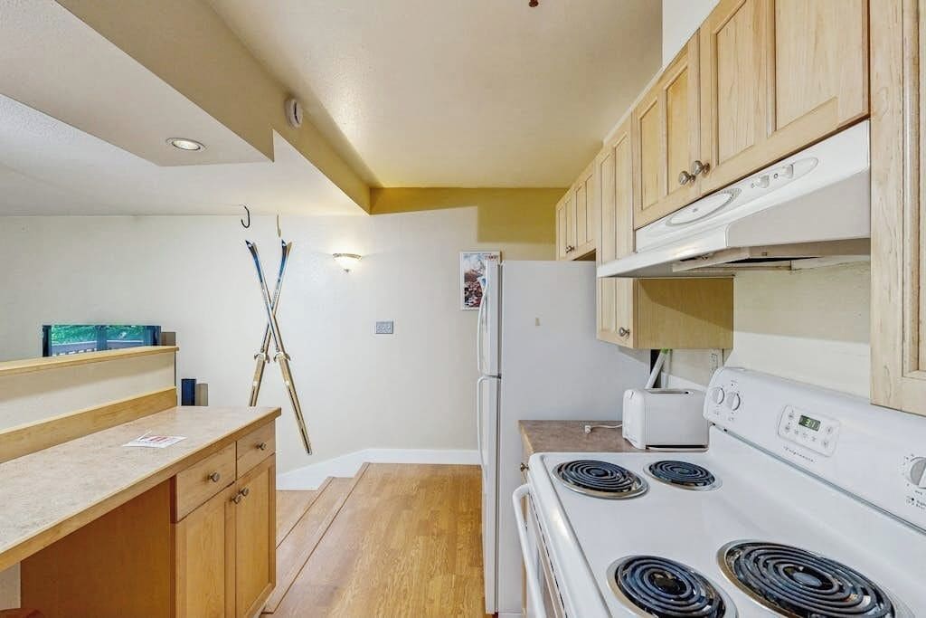 A kitchen with wooden cabinets, a white stove, and a refrigerator.