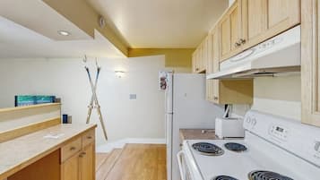 A kitchen with wooden cabinets, a white stove, and a refrigerator.