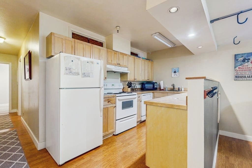 A compact kitchen with a refrigerator, stove, microwave, and wooden cabinets.