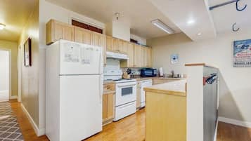 A compact kitchen with a refrigerator, stove, microwave, and wooden cabinets.