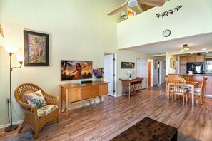 A spacious living area with a dining table, wooden furniture, and a kitchen in the background.