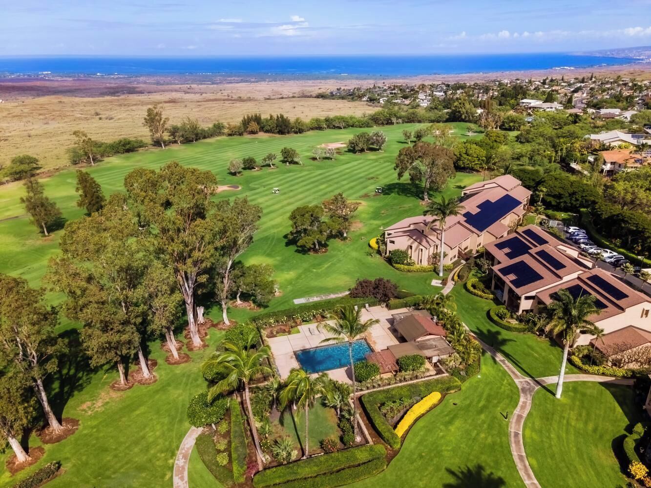Une vue aérienne d’un terrain de golf avec une piscine, des maisons et une vue sur l’océan.