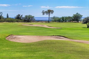 A golf course with bunkers and a clear view of the ocean.