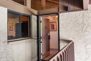A hallway with a door leading to a room, a window with a view, and a textured wall.