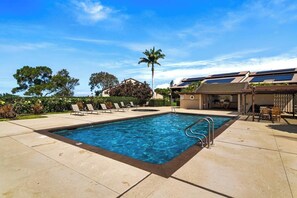 A swimming pool with lounge chairs and a covered patio area.