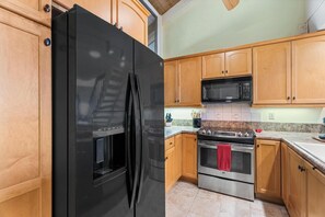A kitchen with wooden cabinets, a black refrigerator, a microwave, and a stove.
