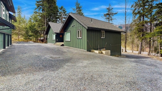 A two-story building with a gravel driveway and a forested background.