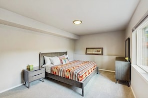 A bedroom with a bed, nightstand, dresser, and a window. - Cozy Mountainside Duplex Near Virgin Creek Trailhead (Girdwood)