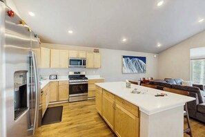 A modern kitchen with stainless steel appliances, wooden cabinets, and a central island.