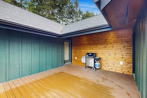 A covered outdoor area with a wooden deck, a grill, and a cleaning cart.