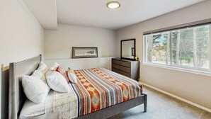A bedroom with a bed, dresser, and a large window.