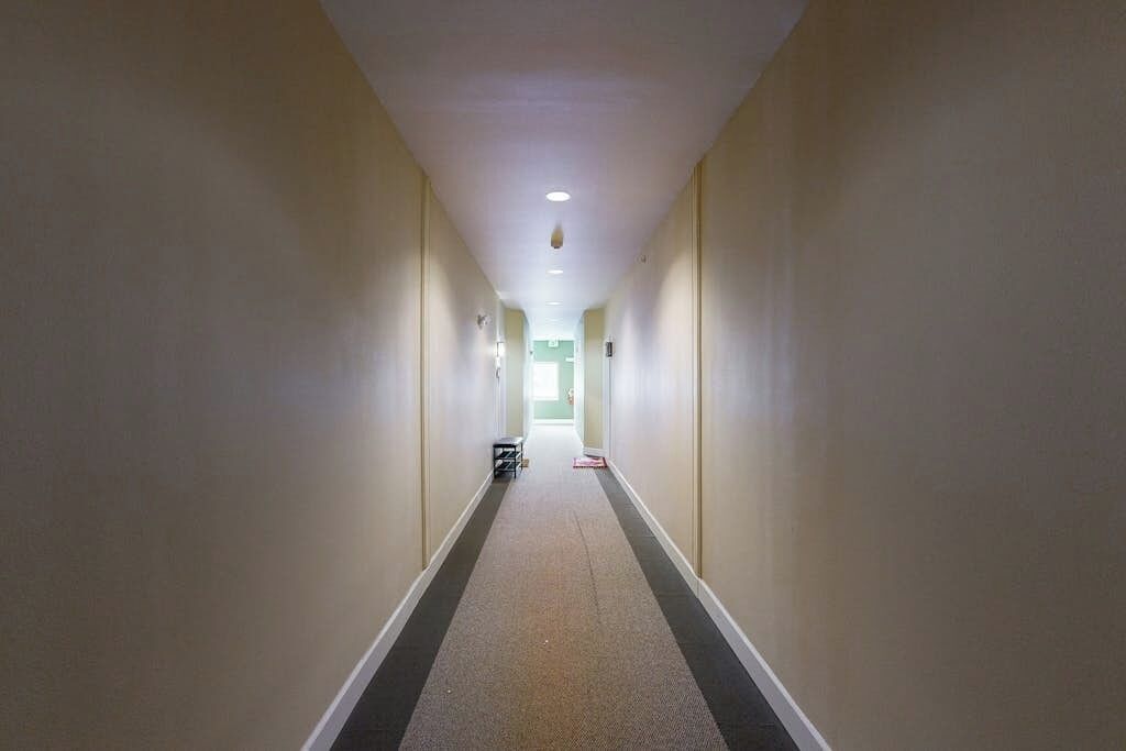 A long, narrow hallway with a carpeted floor and white walls.