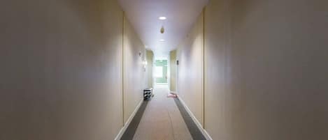 A long, narrow hallway with a carpeted floor and white walls.