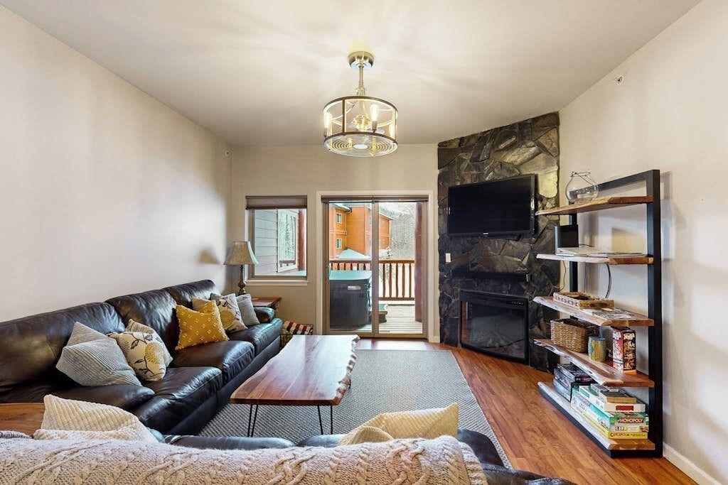 A living room with a leather sofa, a coffee table, a fireplace, and a bookshelf.