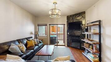 A living room with a leather sofa, a coffee table, a fireplace, and a bookshelf.