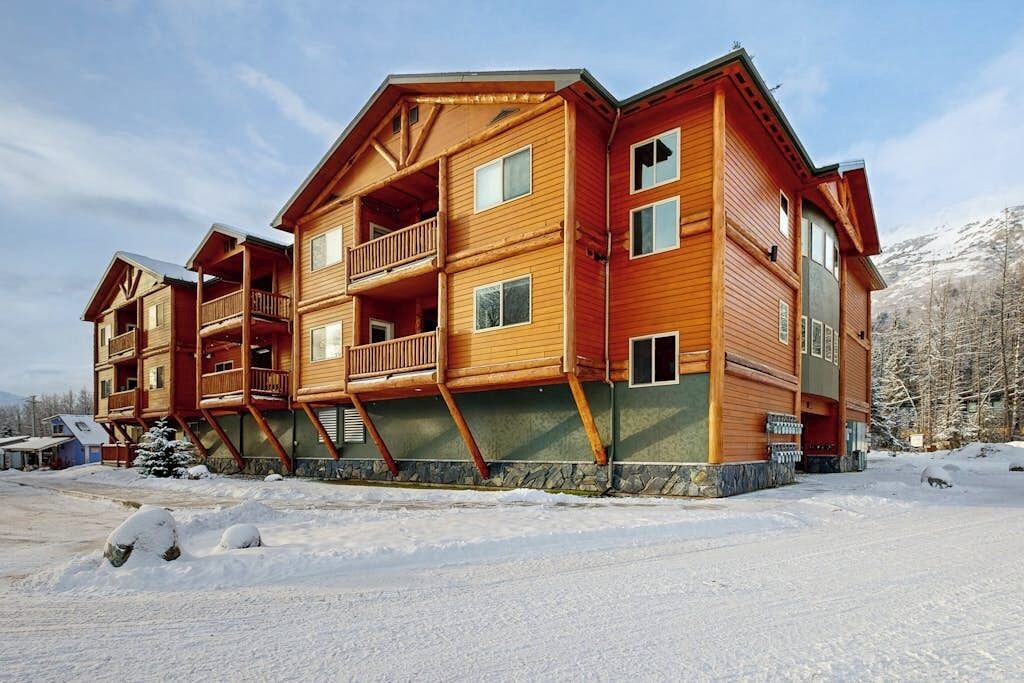 A multi-story log cabin with balconies and a stone foundation.