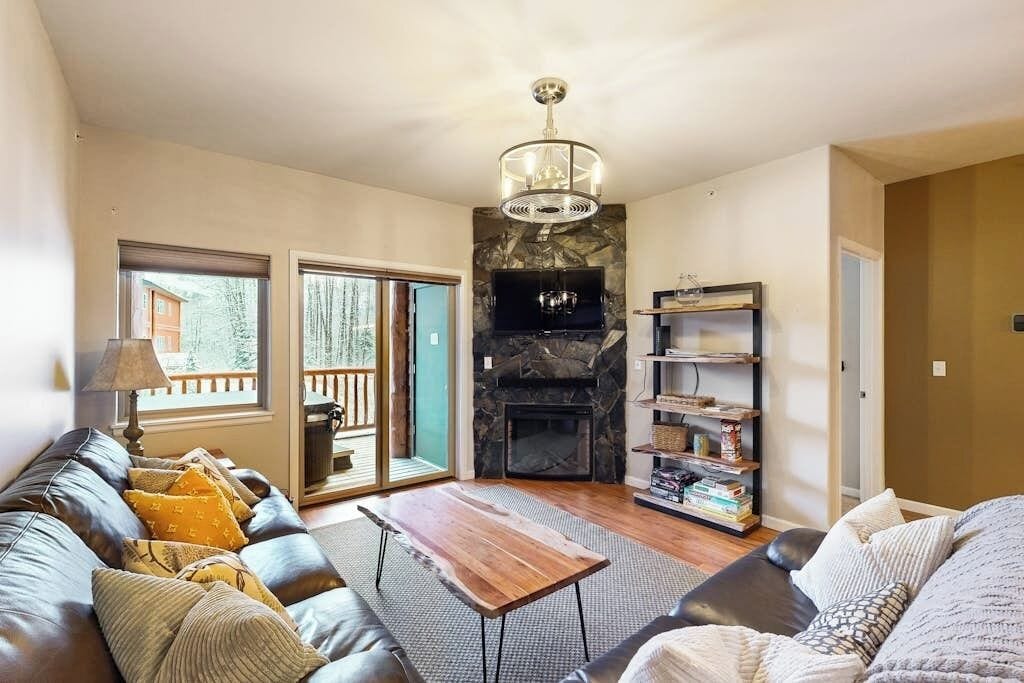 A living room with a fireplace, a sofa, a coffee table, and a bookshelf.