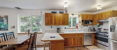 A kitchen with wooden cabinets, a stainless steel refrigerator, and a dining area with a table and chairs.
