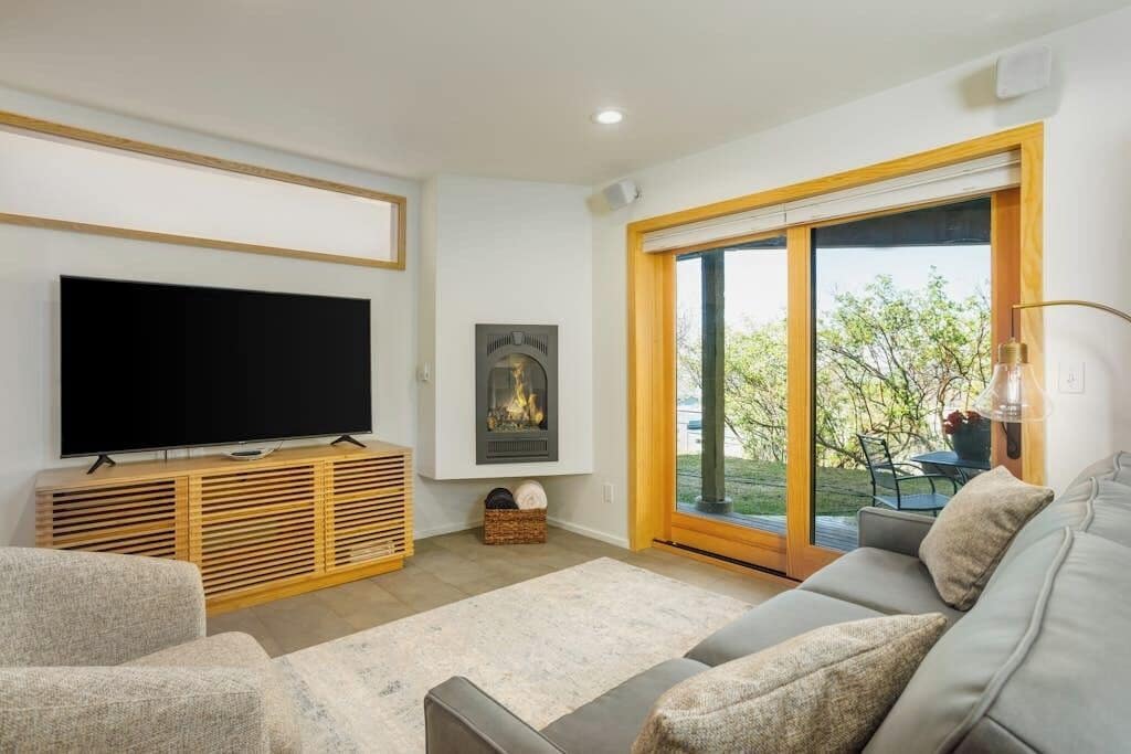 A living room with a flat-screen TV, a fireplace, a sofa, and a sliding glass door leading to an outdoor area.