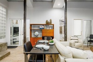 A dining area with a table set for two, a sofa, and a bookshelf with various items. - Luxury Townhouse w/ Hot Tubs & Inlet Views, Walk (Anchorage)