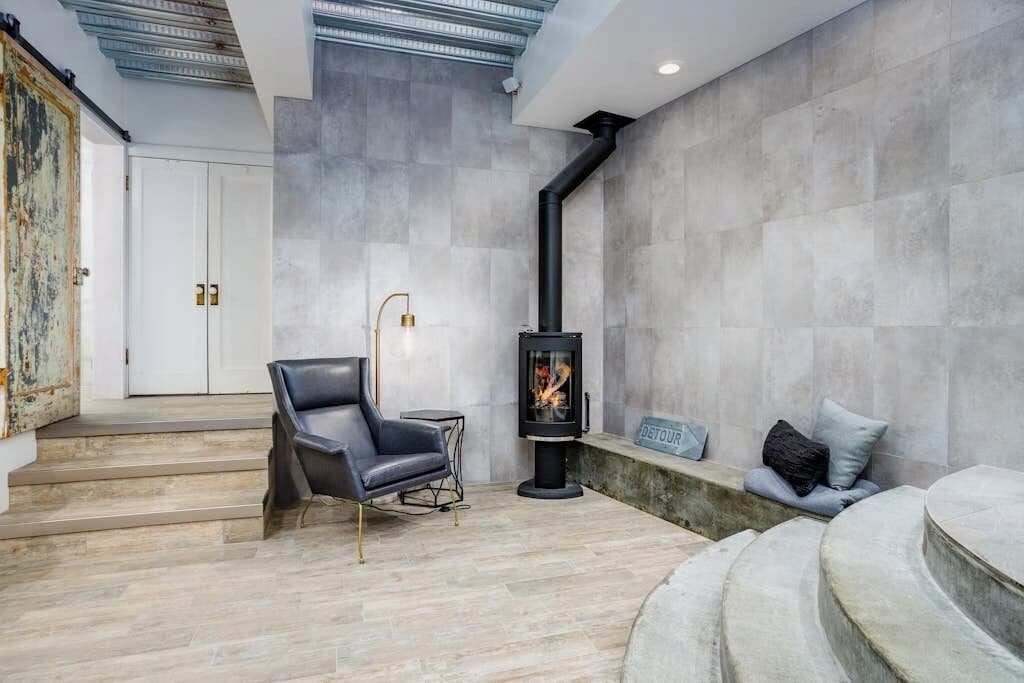 A modern interior with a fireplace, a leather chair, and a bench.