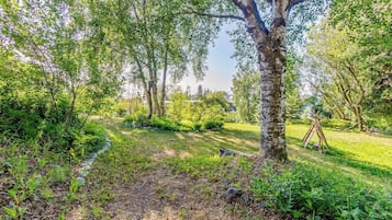 A garden with a dirt path, trees, and a wooden structure.