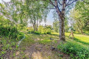 A garden with a dirt path, trees, and a wooden structure.
