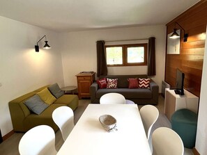 A compact living space with a sofa, a dining table, and a television. - Apartment with parking - 6 guests (Valloire)