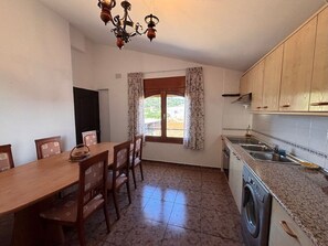 Una cucina con tavolo e sedie, una lavatrice e una finestra con tende.