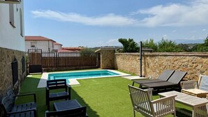 A backyard with a swimming pool, artificial grass, and outdoor furniture.