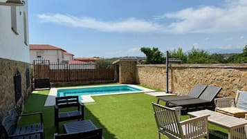 A backyard with a swimming pool, artificial grass, and outdoor furniture.