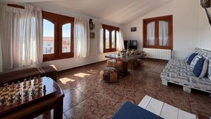 A spacious living area with a wooden coffee table, a sofa, and a chessboard.