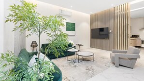 Een moderne woonkamer met een bank, een salontafel, een televisie en een keuken in de achtergrond.