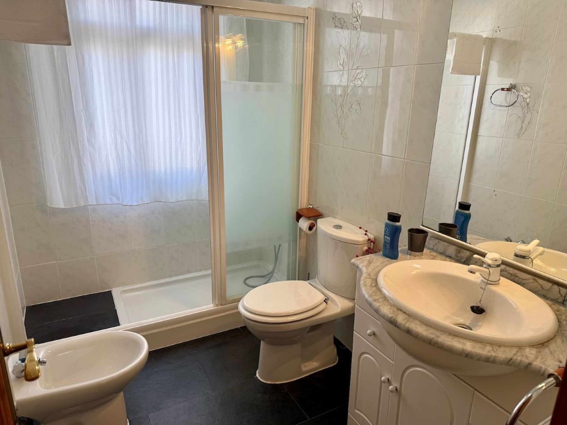 Un baño con inodoro, bidé y lavamanos.