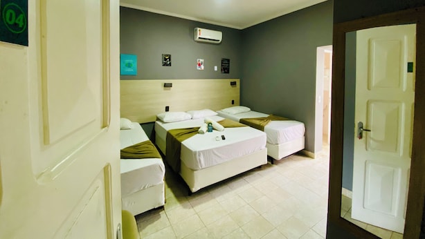 Una habitación de hotel con tres camas, un ventilador de techo y una puerta.