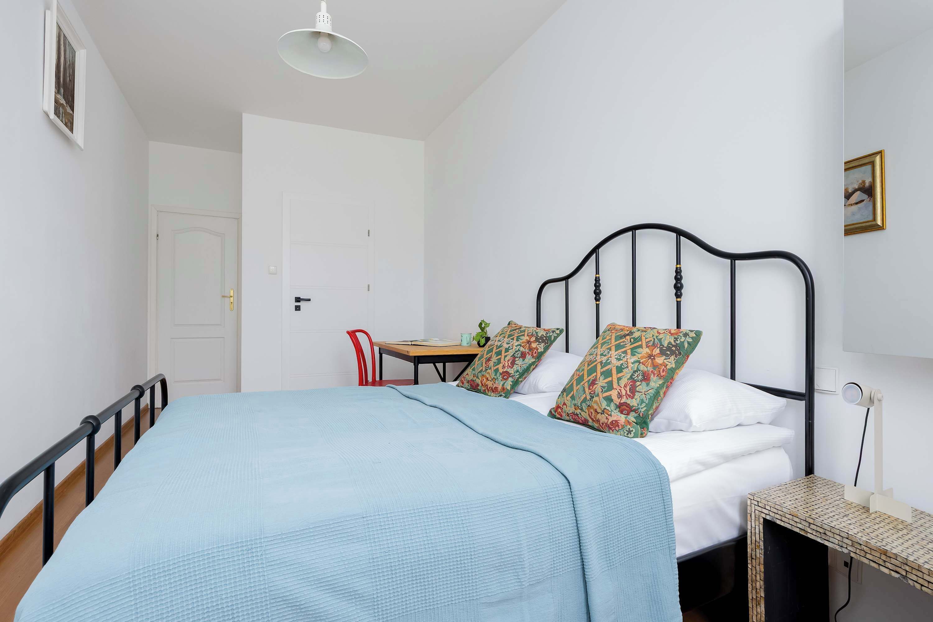 A bedroom with a bed, a desk, a chair, and a door.