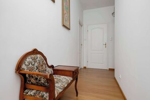 A hallway with a wooden chair and a door. - Cosy Apartment with a Balcony | 2 Bedrooms | Workspace (Warszawa)