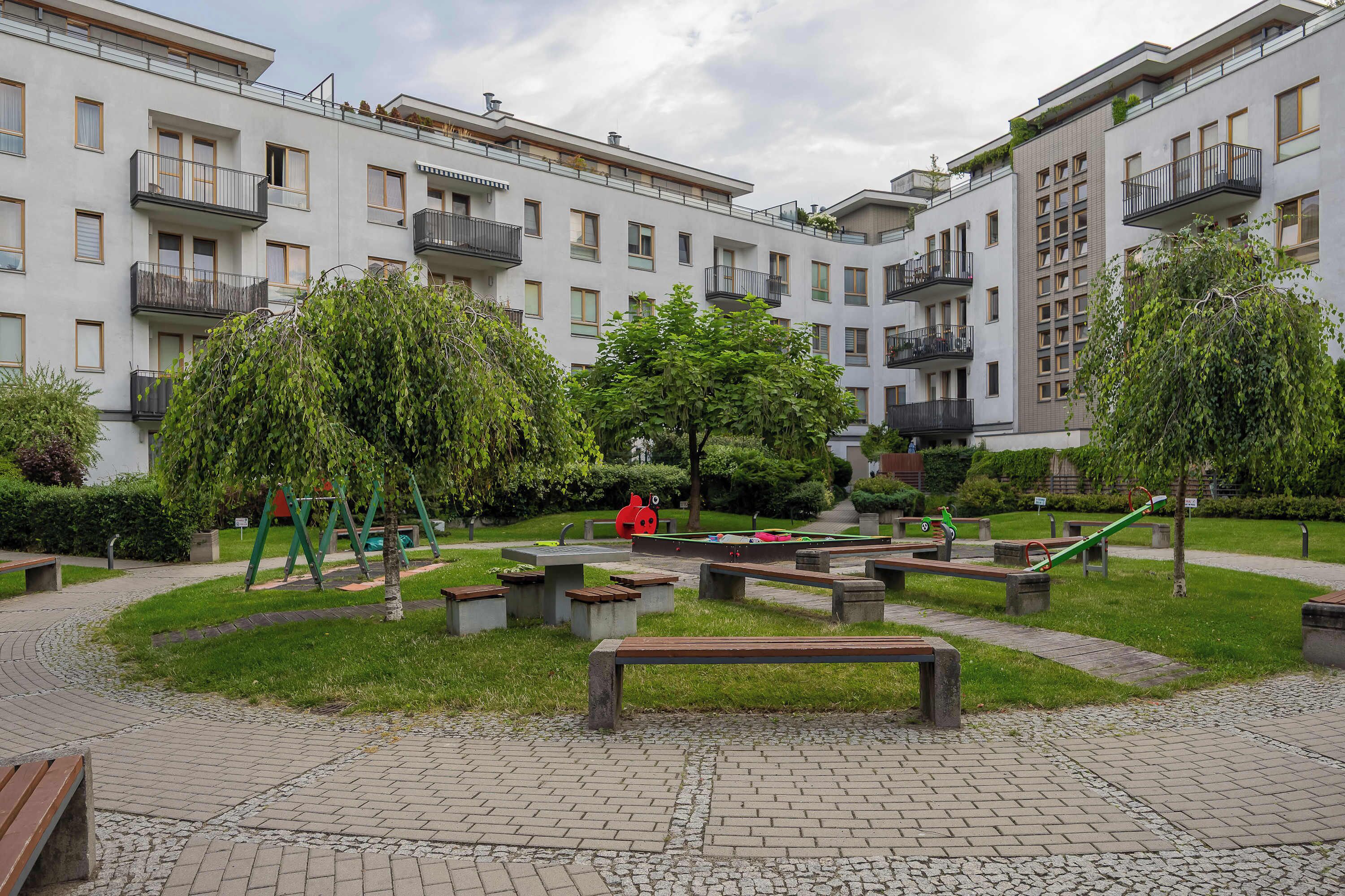 A courtyard with a playground, benches, and a building with multiple balconies.