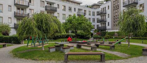 A courtyard with a playground, benches, and a building with multiple balconies.