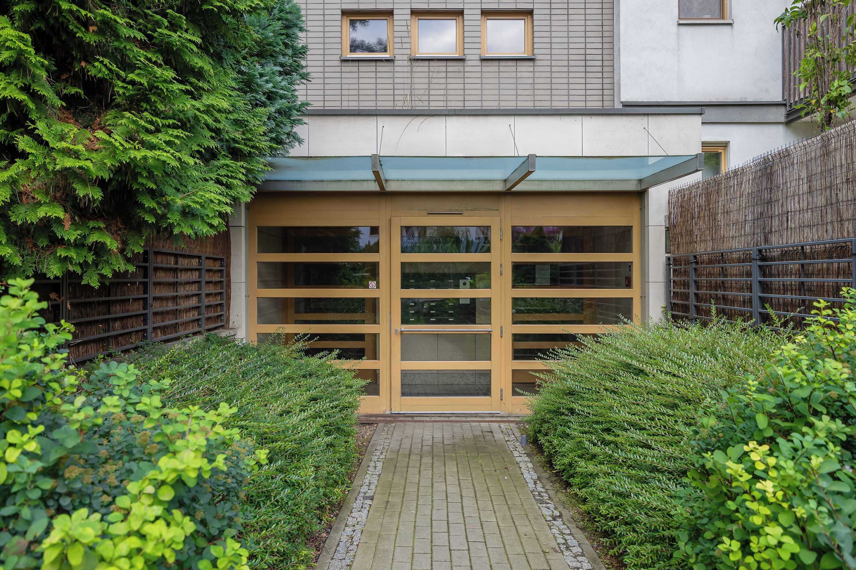 Un bâtiment doté d’une entrée abritée, d’un chemin pavé menant à l’entrée et d’une clôture sur un de ses côtés.
