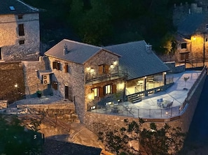 A stone building with a balcony and outdoor seating area.
