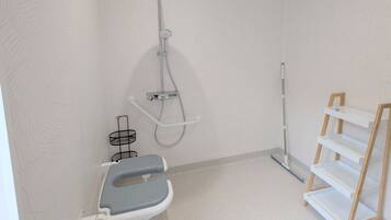 Een badkamer met een douche, toilet en een opbergmeubel.